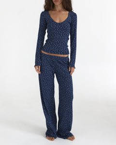 Woman wearing a navy blue pajama set with white floral pattern on a white background