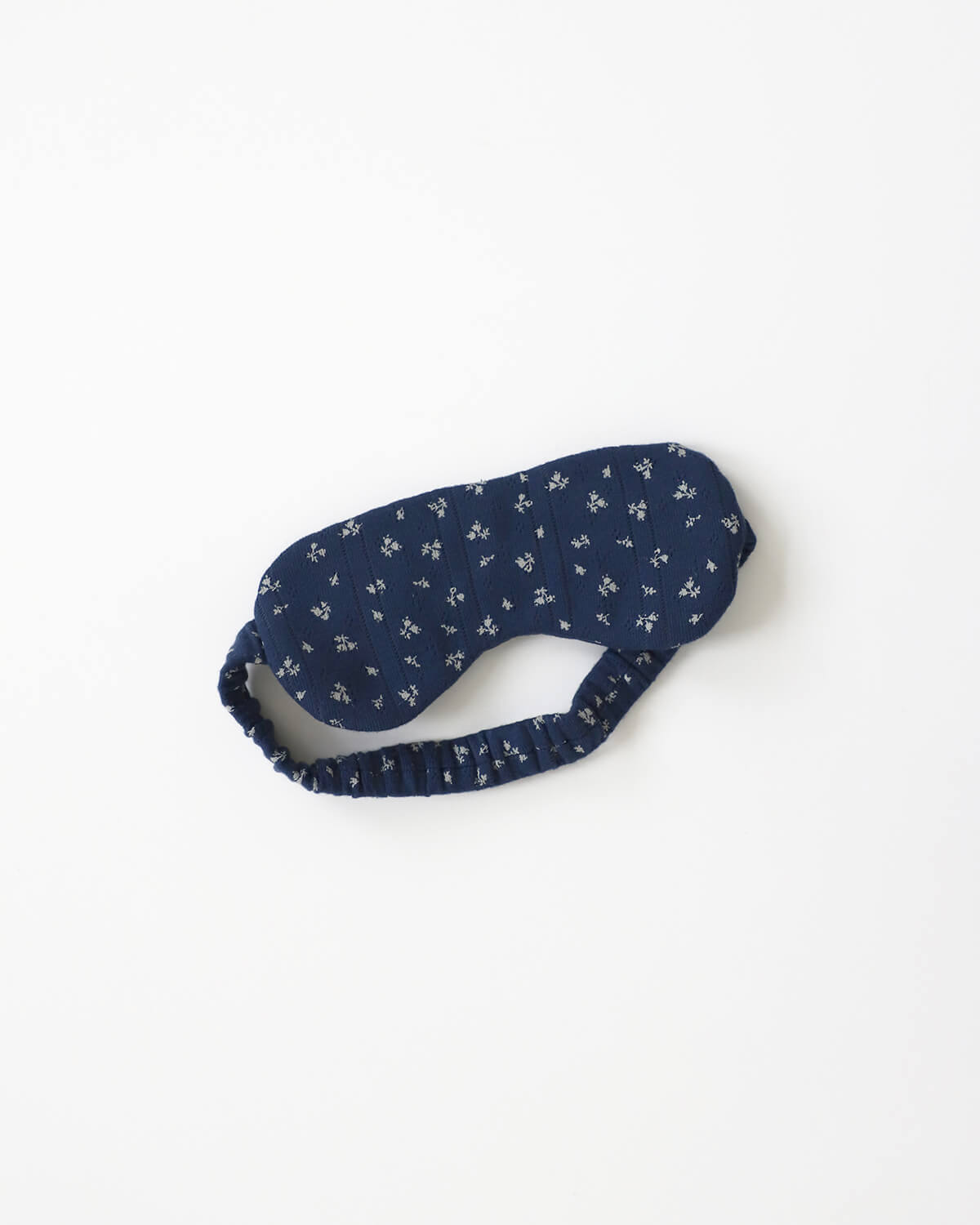 Navy blue sleep mask with white floral pattern on a white background
