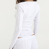 White top with long sleeves and matching trousers on a plain background