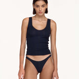A model wearing a dark navy top and matching underwear, photographed against a clean off-white studio background.