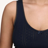 Close-up of a woman wearing a dark navy blue tank top with sheer lace trim along the scoop neckline and a small matching bow at the center front.