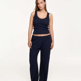 A woman in a matching navy blue loungewear set consisting of a sleeveless cropped tank top and wide-leg pants, photographed against a clean white studio background.