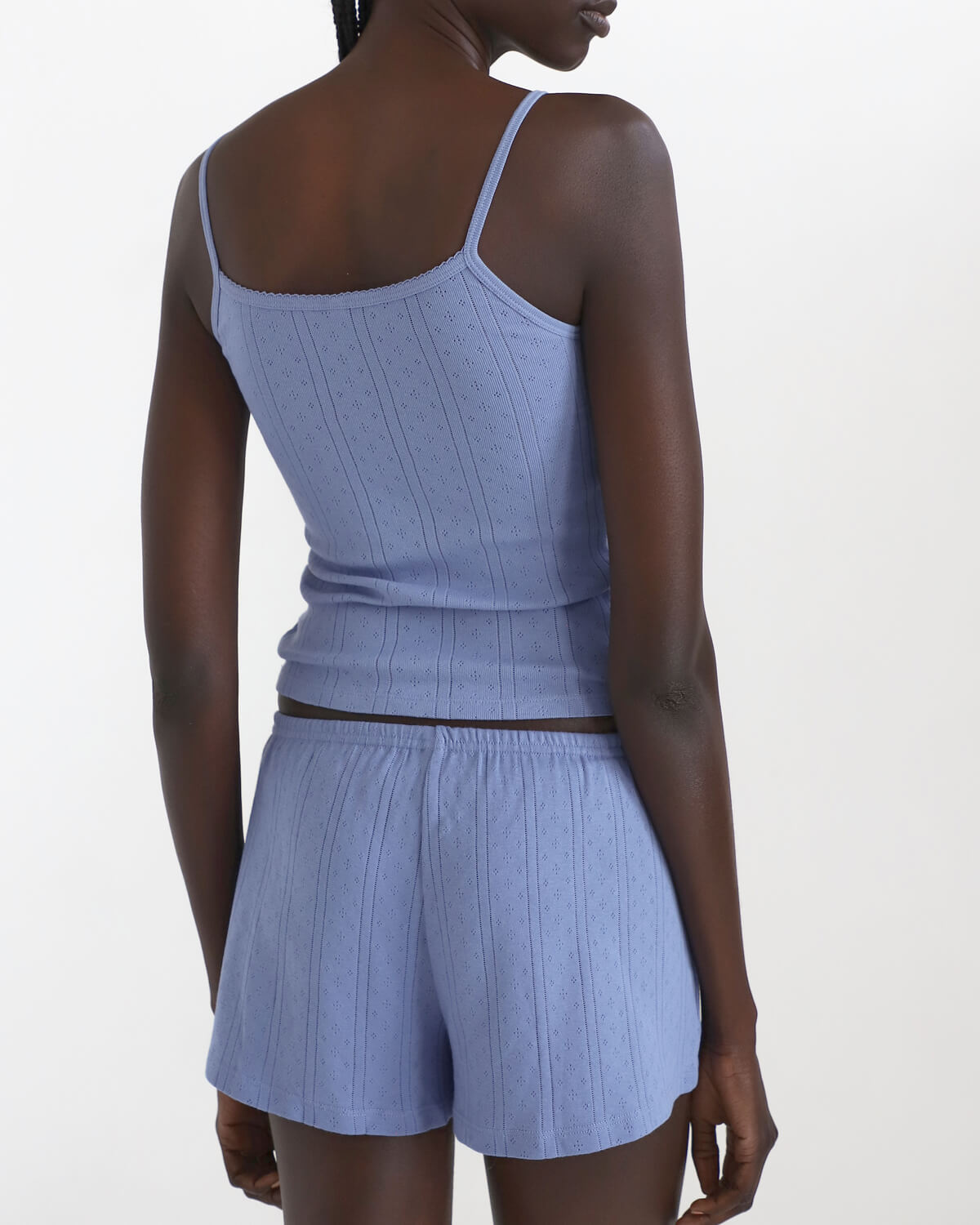 Woman wearing a blue ribbed tank top and shorts set on a white background