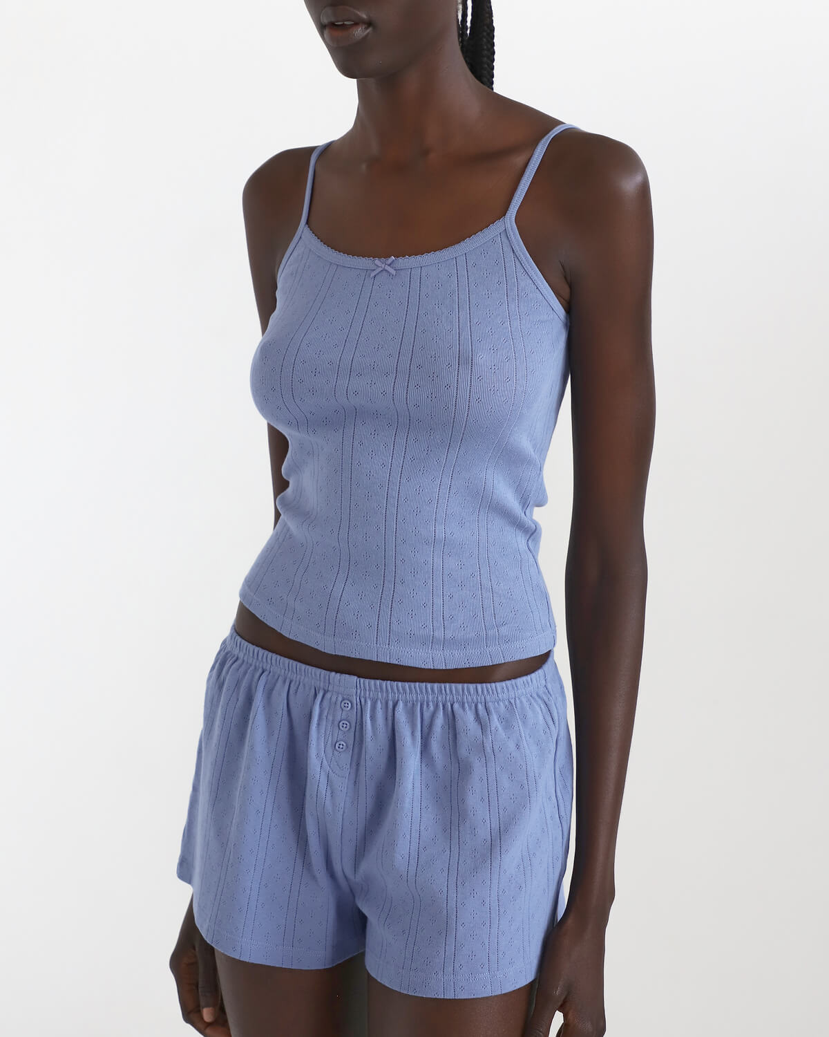 Woman wearing a blue ribbed tank top and shorts set on a white background