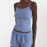 Woman wearing a blue ribbed tank top and shorts set on a white background