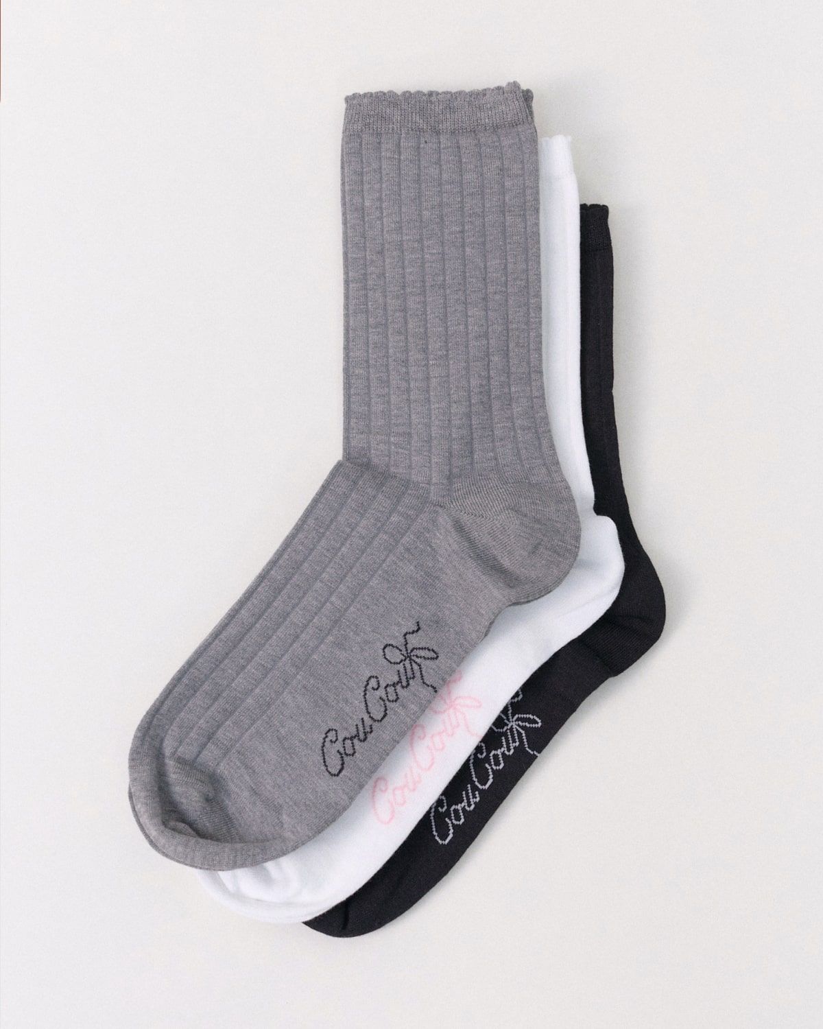 Three socks in gray, white, and black with Cou Cou branding on a light gray background.