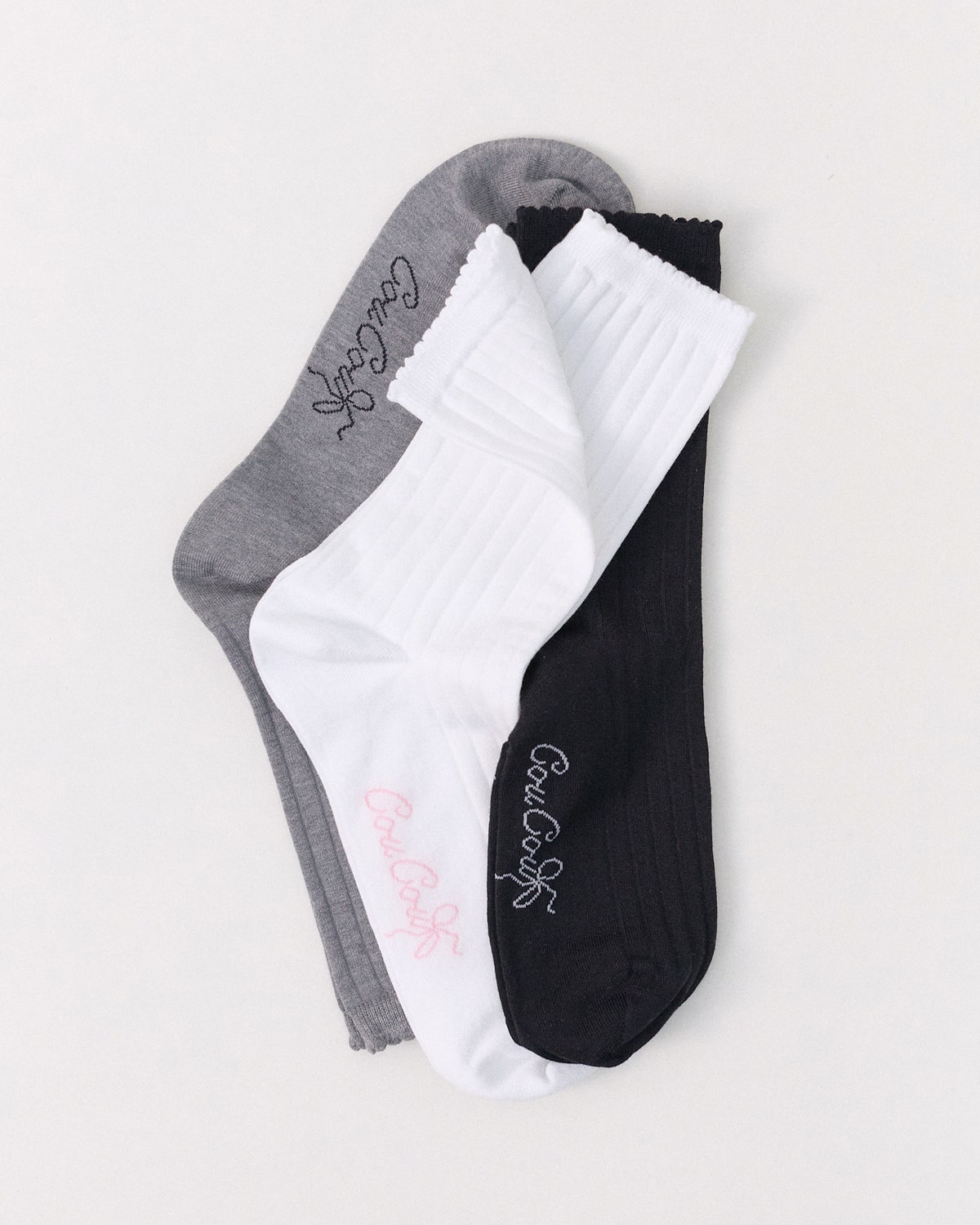 Three pairs of socks in gray, white, and black on a light gray background