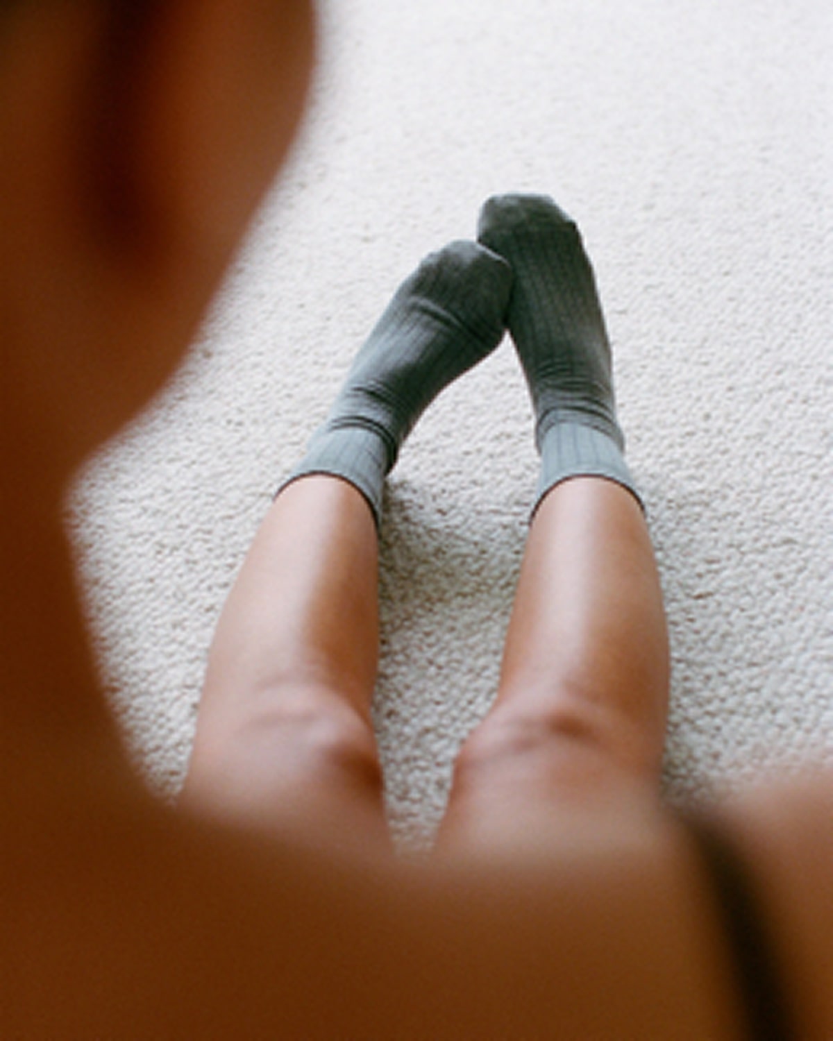 Person wearing gray socks on a light-colored carpet