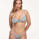 A woman modeling a light gray set against a plain off-white studio background.