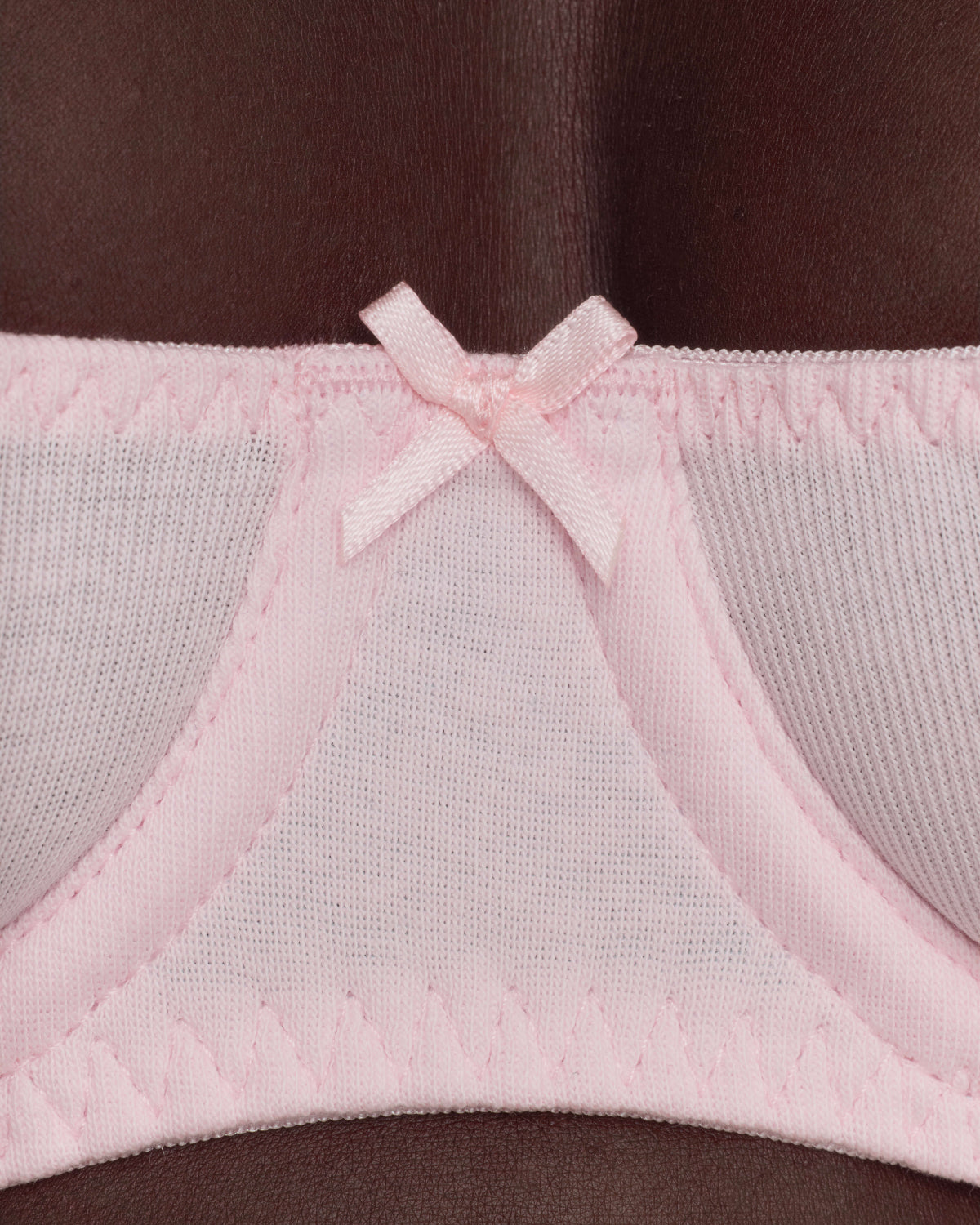 Close-up of a light pink bra and underband with a small bow detail.