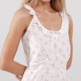 Woman wearing a white floral dress with thin straps on a plain background