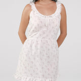Woman wearing a white floral dress on a plain background