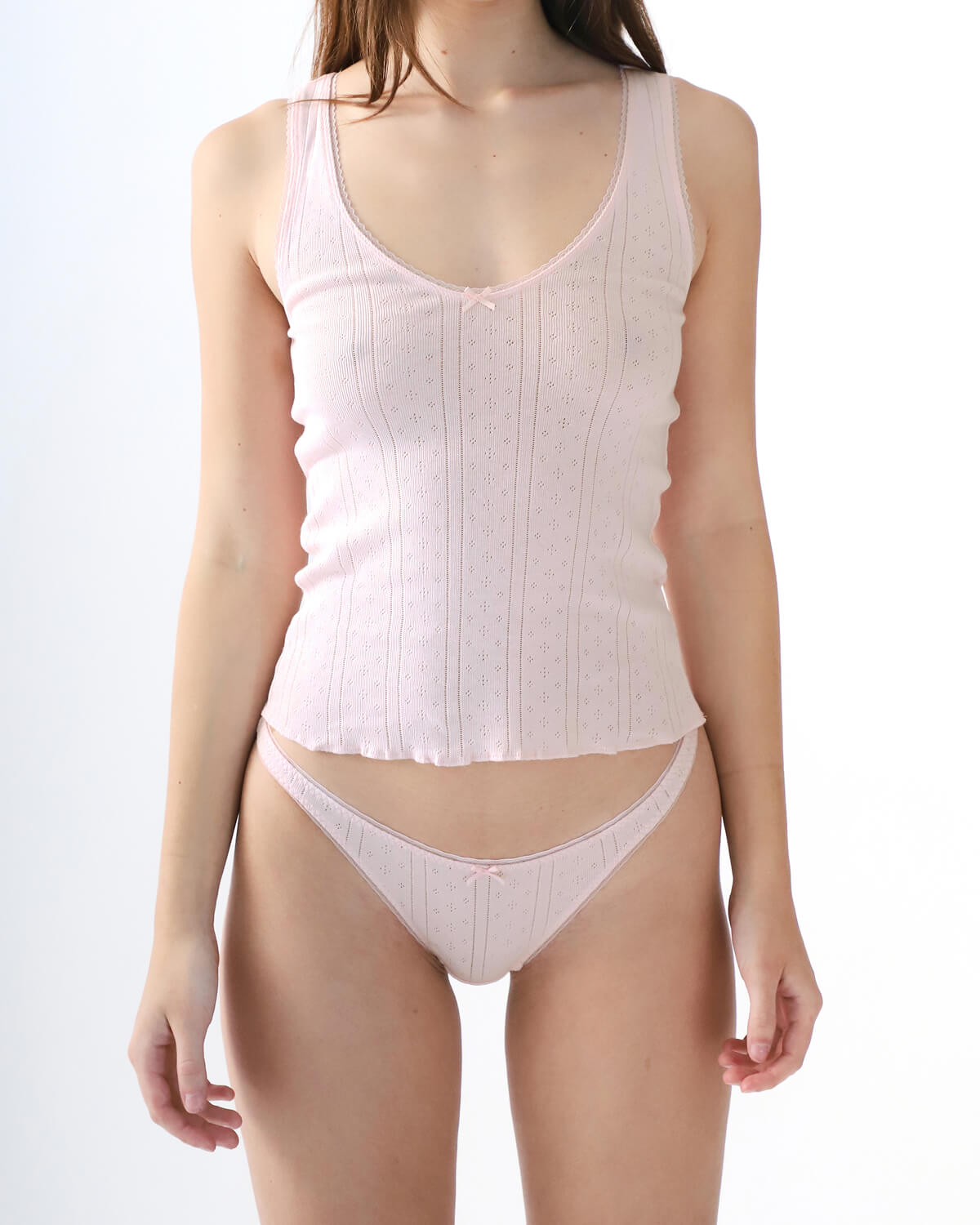 Woman wearing a white ribbed tank top and underwear set on a white background