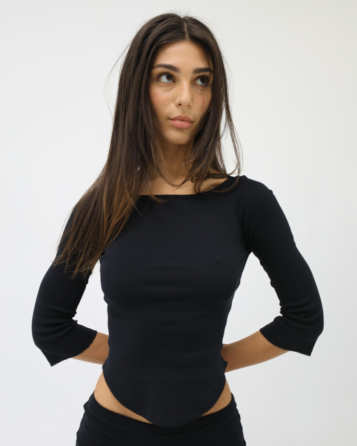 Woman wearing a black long-sleeve top against a white background