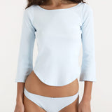 Woman wearing a light blue long-sleeve top and matching underwear on a plain background