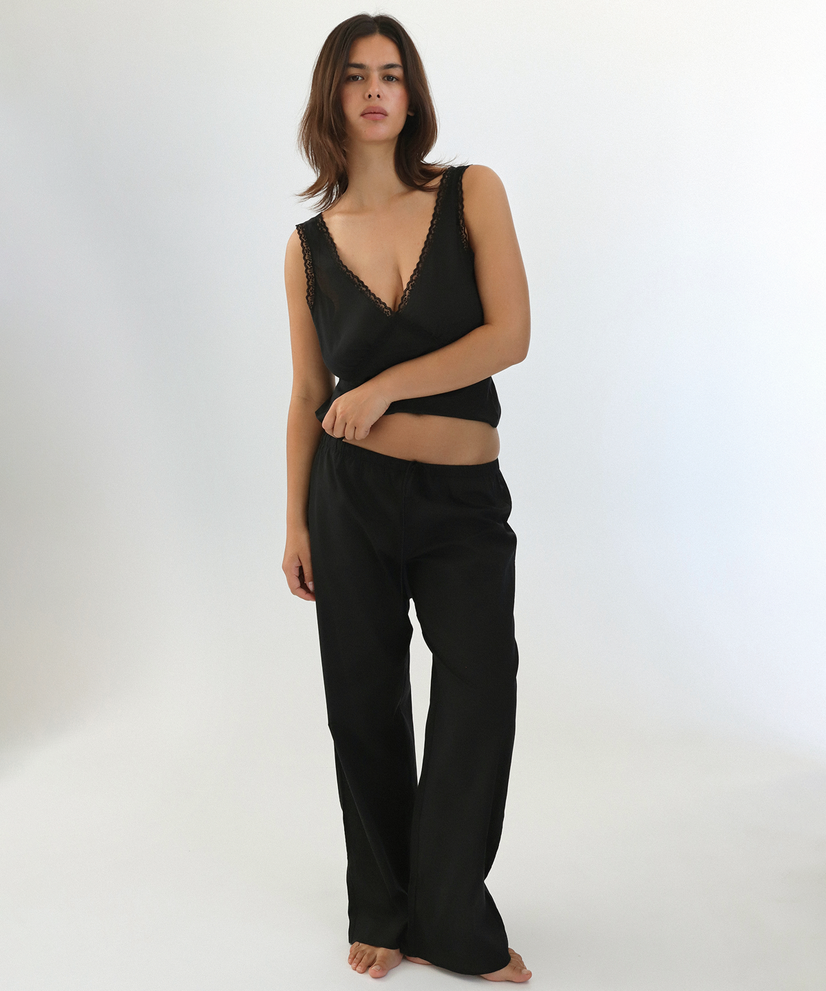 Woman wearing a black sleeveless top and pants on a white background