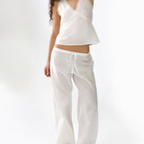 Woman wearing a white sleeveless top and pants on a white background