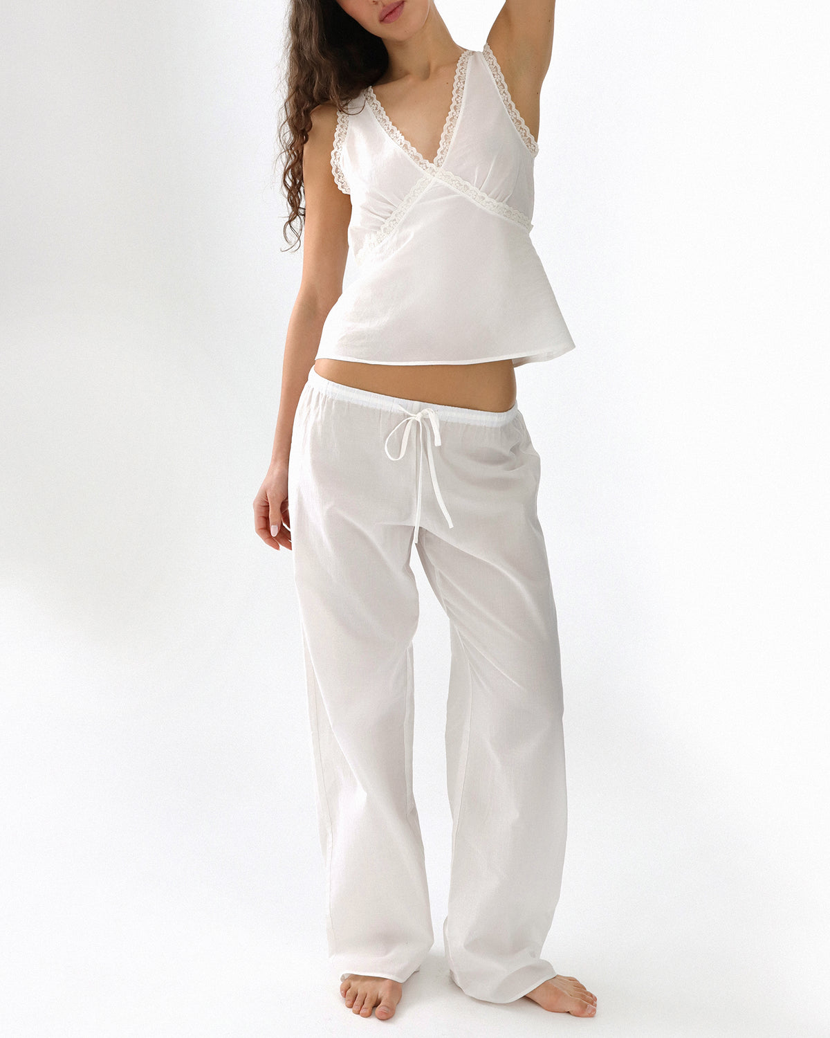Woman wearing a white sleeveless top and pants on a white background