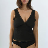 Woman wearing a black lace-trimmed top and underwear set on a white background
