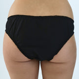 Black briefs worn by a person on a light gray background