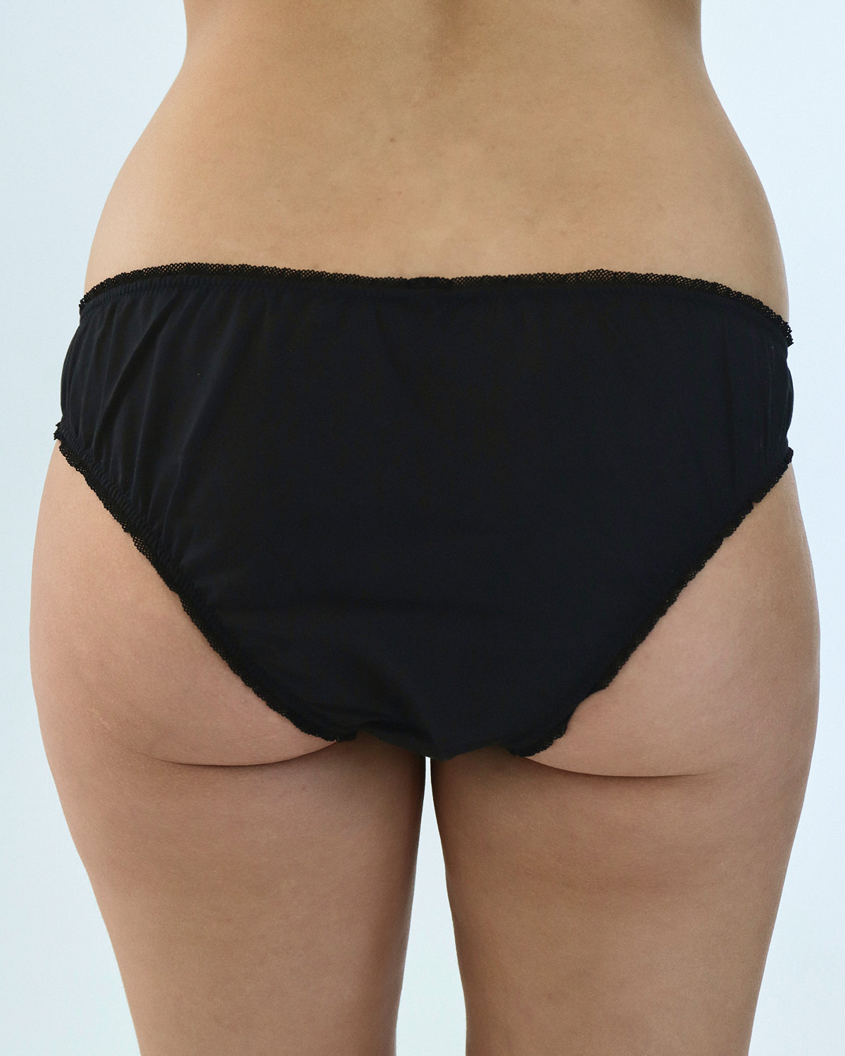 Black briefs worn by a person on a light gray background