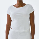 Person wearing a white top and shorts set on a plain background