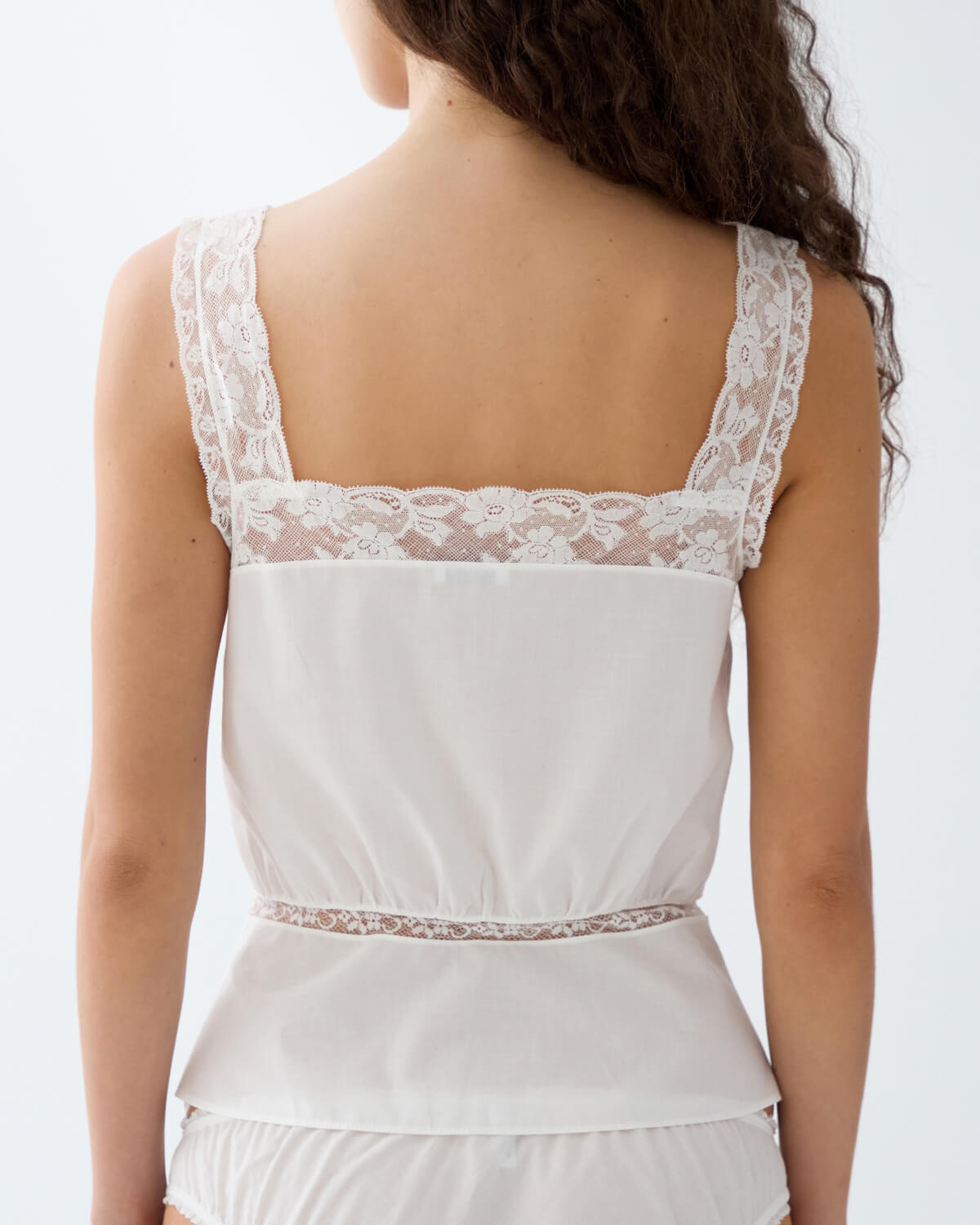 White lace top worn by a person on a plain background
