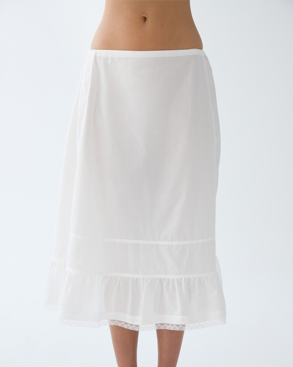 White skirt worn by a person on a plain background
