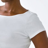 White short-sleeve top worn by a person on a white background