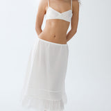 Woman wearing a white lace-trimmed nightgown on a plain background